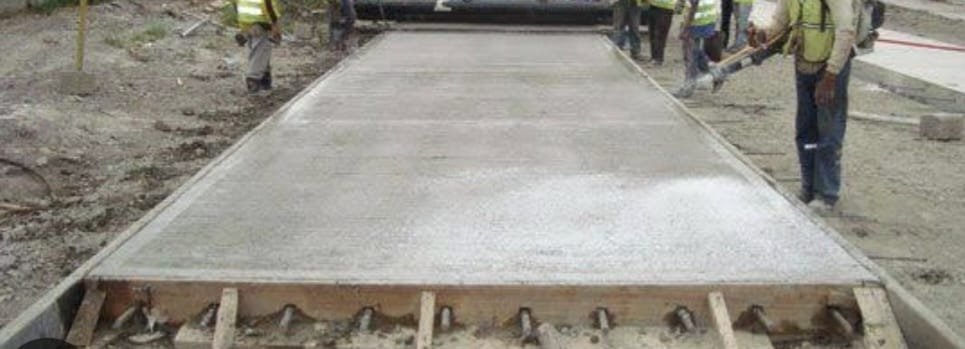 Losa de concreto recién terminada con rieles metálicos y pasadores